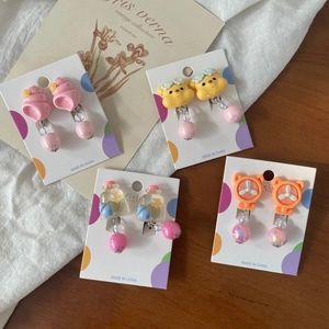 Dettaglio di quattro paia di orecchini a clip in resina per bambini su scheda display