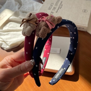 Detail of handmade headbands with star patterns and plush bear bow accents