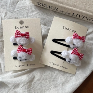 Detail of white plush puppy hair clips with red checkered bows on display card
