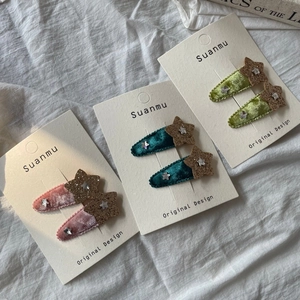 Détail des barrettes en velours avec étoiles dorées pailletées et petits strass brillants