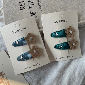 Détail de barrettes en velours avec étoiles en bleu et vert et paillettes brillantes