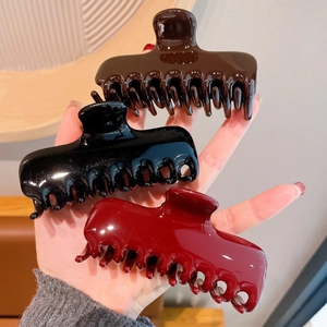 Close-up of three large glossy acrylic hair claws in brown, black and burgundy colors
