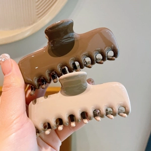 Detail showing two glossy acrylic rectangular hair claws in coffee and cream beige