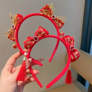 Détail de serre-tête en velours rouge avec paillettes dorées et longues franges