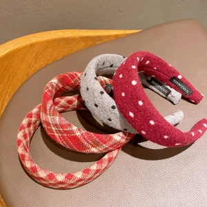 Detail of four padded plaid headbands featuring handmade labels and woolen fabric texture