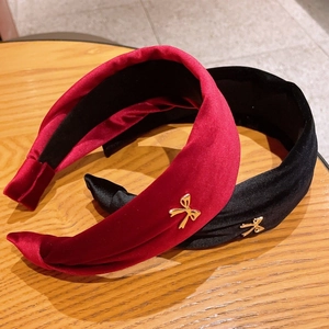 Close-up of velvet headband set with vintage gold metal bow details on wooden surface