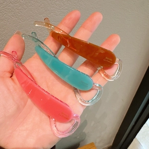 Dettaglio di mollette a banana leggere in resina nei colori arancione, blu e rosa