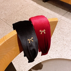 Close-up of velvet wide headbands in black and dark red with small gold metal bows
