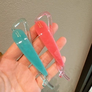 Dettaglio di fermagli a banana verde menta e rosa corallo con scritte dorate sulla resina