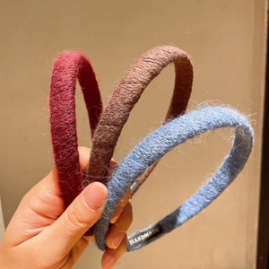 Close-up of three handmade knitted headbands in burgundy, coffee, and morandi blue