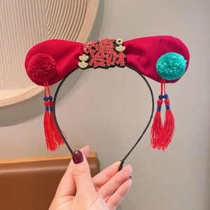 Détail d'un serre-tête en velours rouge avec nœud papillon et caractères festifs