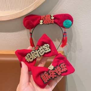 Détail de l'ensemble bandeau Nouvel An en velours rouge avec broderies et pompons