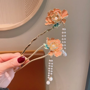 Detail of golden U-shaped hairpins with enamel flowers, pearls, and long tassels
