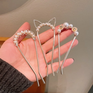 Detail of three pearl U-shaped hairpins with rhinestones in elegant floral and cat ear shapes