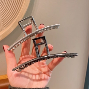 Detailweergave van zilveren en gunmetal metalen haarklemmen vastgehouden door een hand