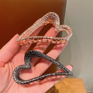 Gedetailleerd zicht op hartvormige metalen haarklemmen met elegante gehamerde textuurafwerking