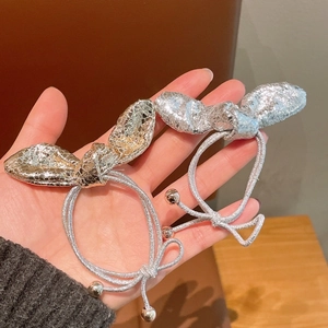 Dettaglio degli elastici per capelli in pelle metallizzata oro e argento con fiocchi
