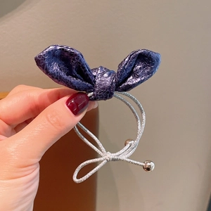 Dettaglio dell'elastico per capelli viola testurizzato con cordino argento e perline