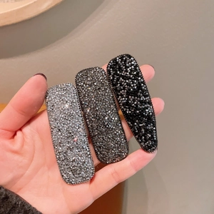 Detailansicht von drei schimmernden Strass-Haarklammern in Silber, Grau und Schwarz