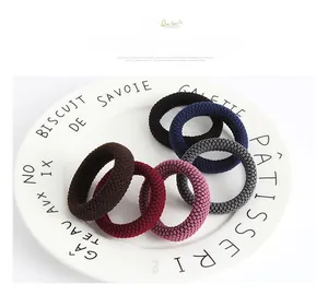 Detail of high-elastic knitted hair ties in six colors shown on a white ceramic plate