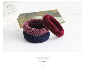 Close-up of three knitted hair bands in blue, pink, and red with honeycomb texture