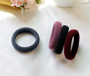 Close-up of four thick elastic hair ties in grey, pink, black, and red with knit texture