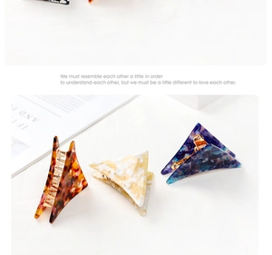 Three acetate triangle hair claws in tortoiseshell, cream, and blue marble patterns