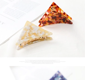 Detail of triangle acetate hair claws with marble and amber patterns and golden metal clips