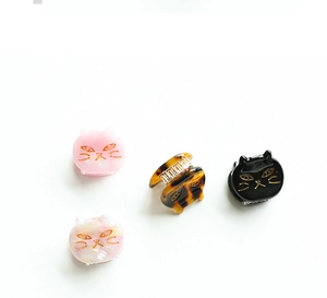 Close-up of four cat-shaped acetate hair clips in black, pink, tortoiseshell and pearl white
