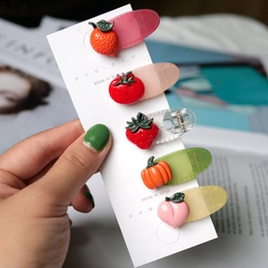 Détail de cinq pinces à cheveux en résine aux motifs de fruits colorés sur carte