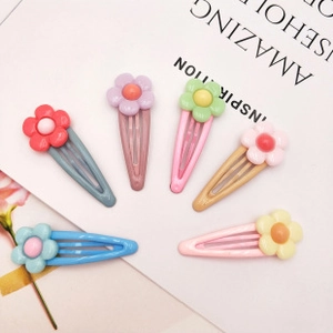Détail de 6 barrettes à fleurs aux couleurs macaron sur fond de magazine blanc élégant