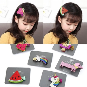 Détail de 6 barrettes en tissu coloré avec motifs de dessins animés sur carton gris