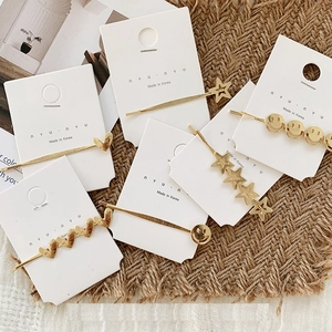 Trendy gold alloy hair clips set with star, heart, and smiley face shapes on display card