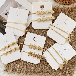 Detail of golden metal hair clips featuring heart and star patterns on card