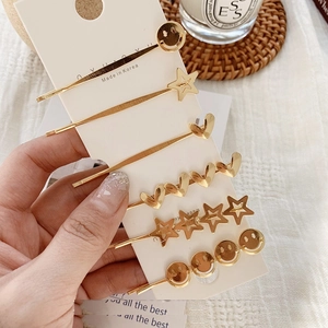 Set of 6 gold alloy hair clips featuring stars and hearts on a white display card