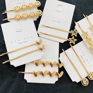 Detailed view of gold metal hair clips with star, heart and smiley face designs