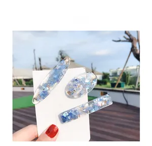 Detailed view of three blue resin hair clips with shell fragments and gold leaf accents