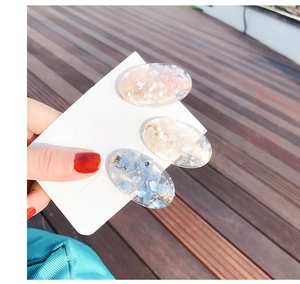 Detailed close-up of three shell-texture resin hair clips in pink, cream and blue colors