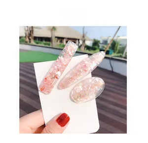 Detailed view of three pink glitter hair clips with shell-like texture in different shapes