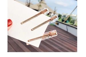 Detail of three-piece hair clip set with marble, floral and glitter patterns on metal base
