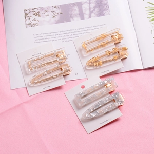 Detail of glitter gold foil acetate hair clips set on white card with soft pink backdrop