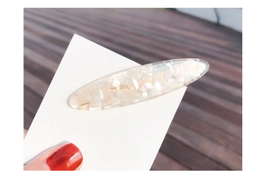 Close-up of a shell-patterned resin hair clip with pearl-like textures and shimmering flakes
