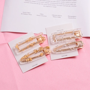 Chic 4-piece acetate hair clip set with gold and silver leaf flakes on a pink fabric background