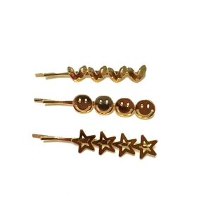 Three-piece set of golden metal hair clips with heart, smiley face, and star designs