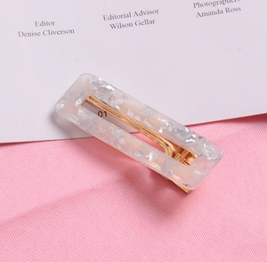 Detailed view of rectangle resin hair clip with silver flakes and golden metal base