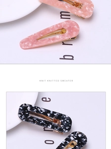 Detail view of acetate leopard print hair clips with high-gloss gold metal duckbill clamps