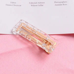 Detailed close-up of a gold metal hair clip featuring glittery acrylic inlay and a hollow design