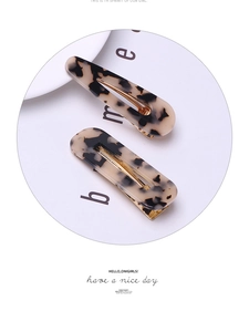 Detail of cream leopard print acetate hair clips set with golden metal duckbill base