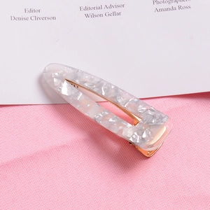 Close-up of gold foil acetate hair clip with hollow oval design and shell texture