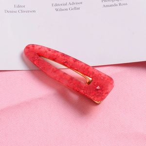 Detail view of red glitter resin hair clip with gold metal snap buckle and texture